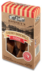 A rectangular cardboard box of fudge with a window cut out in the middle that shows fudge pieces in a wrapped bag. The top of the box has red lines running down it. The box says 'Cherry Bakewell Fudge'.