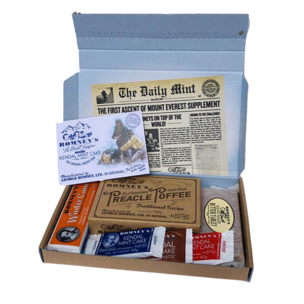 An open rectangular cardboard box containing a variety of Romney's confectionery products such as: rum and butter bar, winter candy bar, 40g white kendal mint cake, 40g brown kendal mint cake, 40g chocolate coated kendal mint cake, butter tablet bar, box of old fashioned treacle toffee