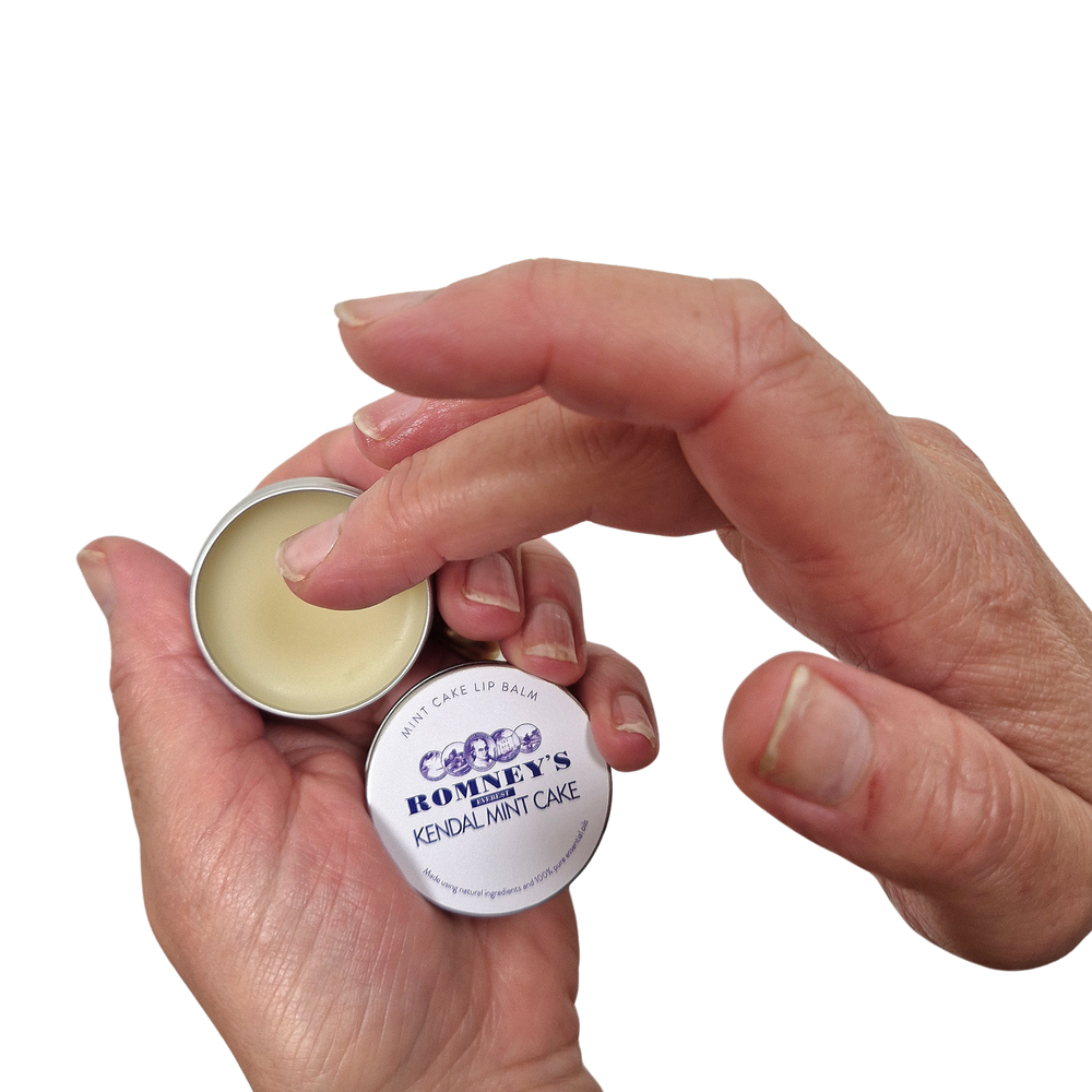 A pair of hands showing off the Romney's Kendal Mint Cake Lip Balm which has been opened.